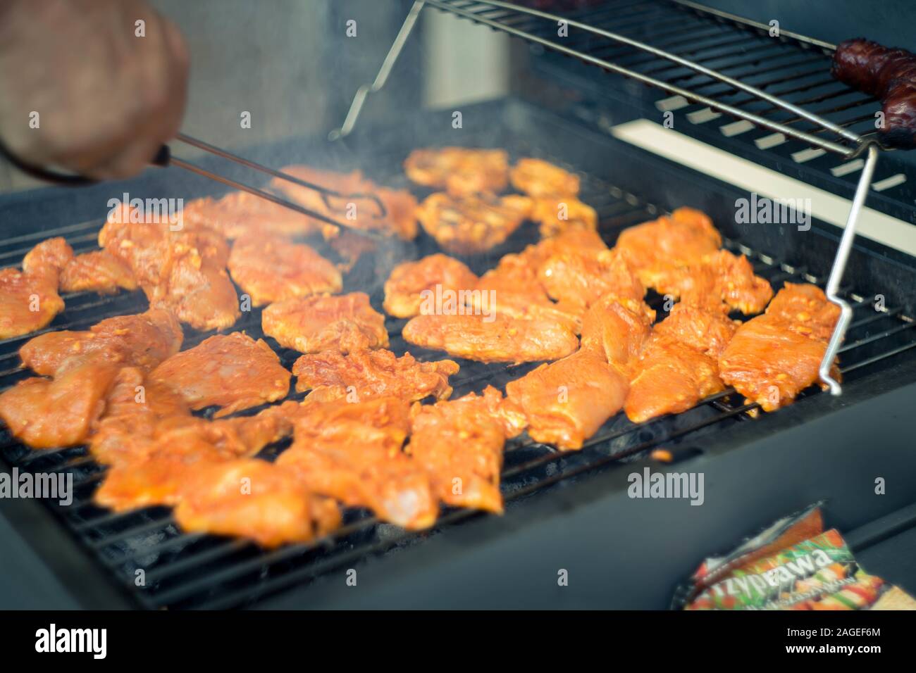 Lot of seasoned meat being barbecued on a grilling machine Stock Photo