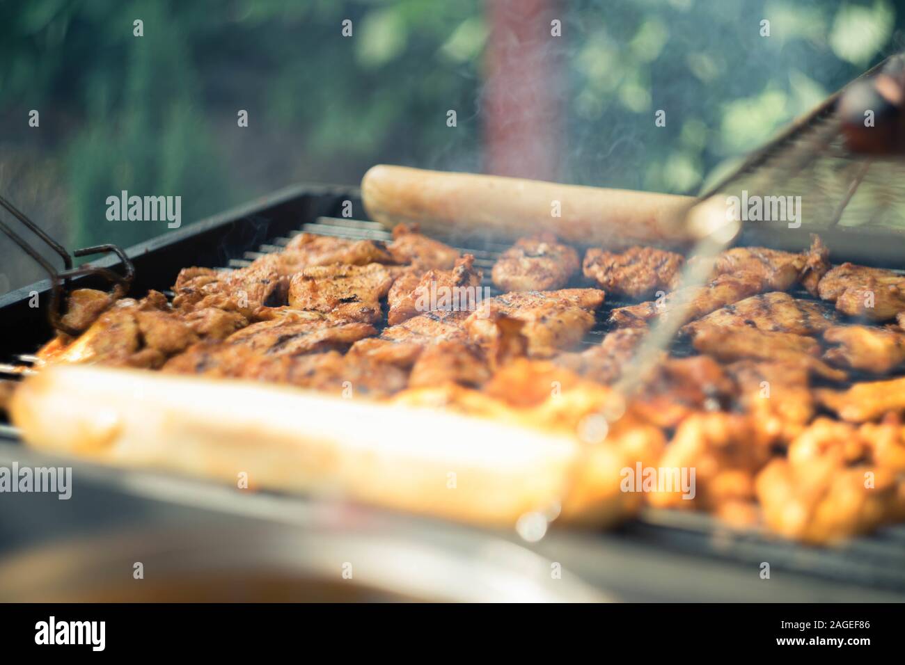 Lot of seasoned meat being barbecued on a grilling machine Stock Photo