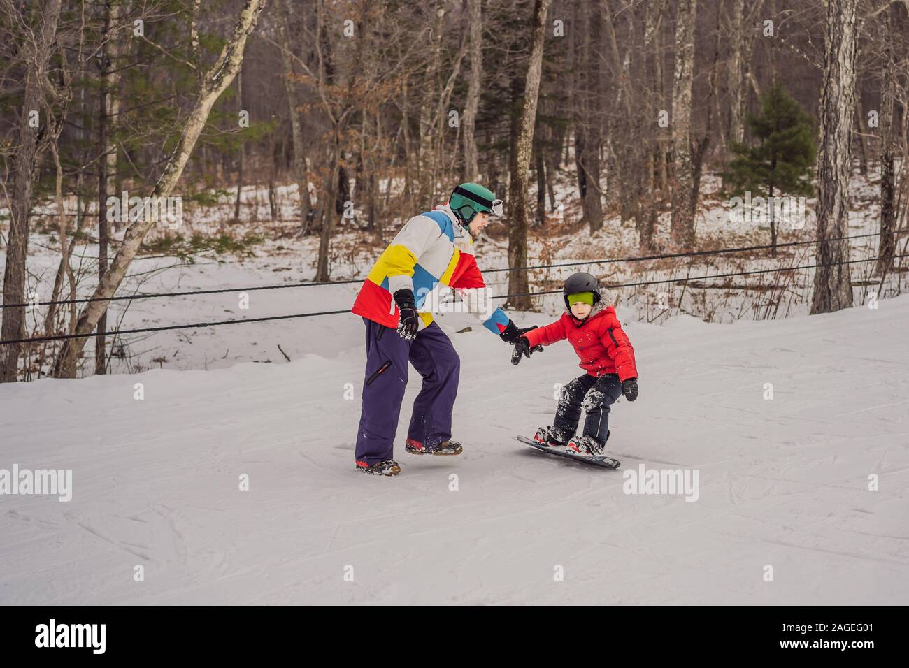 Snowboard instructor teaches a boy to snowboarding. Activities for children in winter. Children's winter sport. Lifestyle Stock Photo