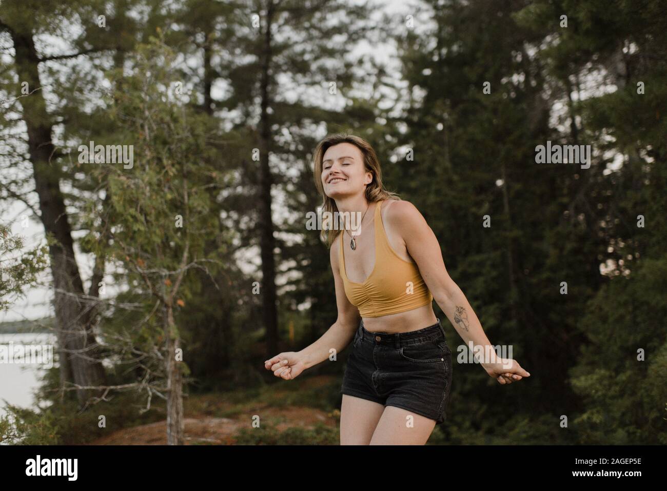 Woman dancing with eyes closed in forest Stock Photo