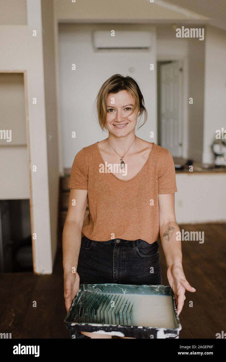 Woman carrying tray of paint in new home Stock Photo