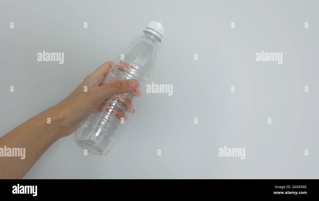 Hand holding an empty transparent plastic water bottle with the cap on. Stock Photo