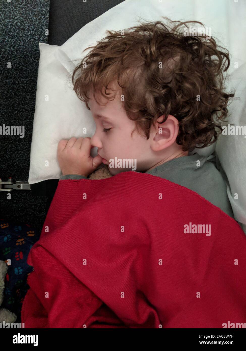 Little boy sleeping on the plane sucking his thumb Stock Photo