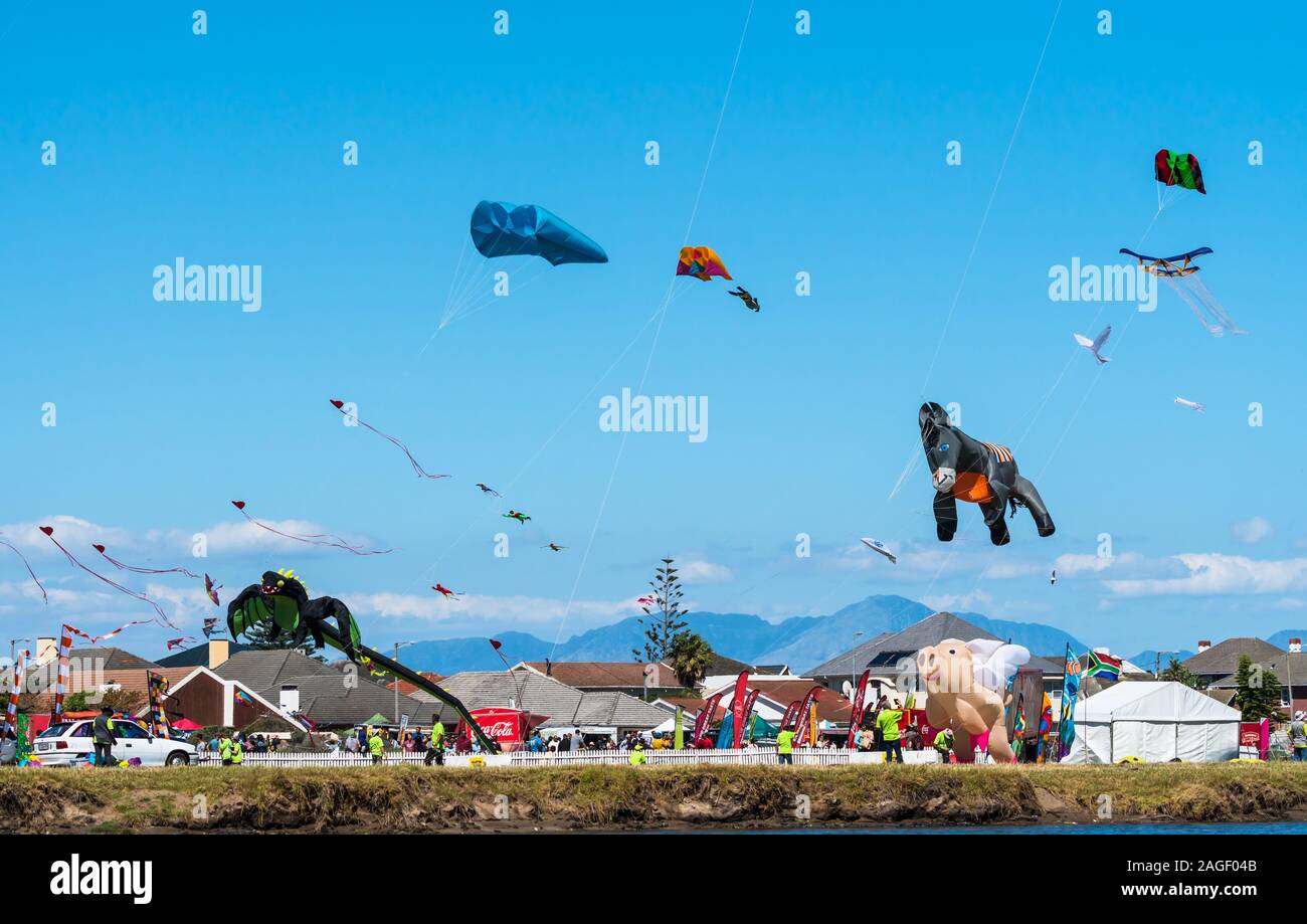 Kite festival with variety of unique kites flying in a blue sky in a