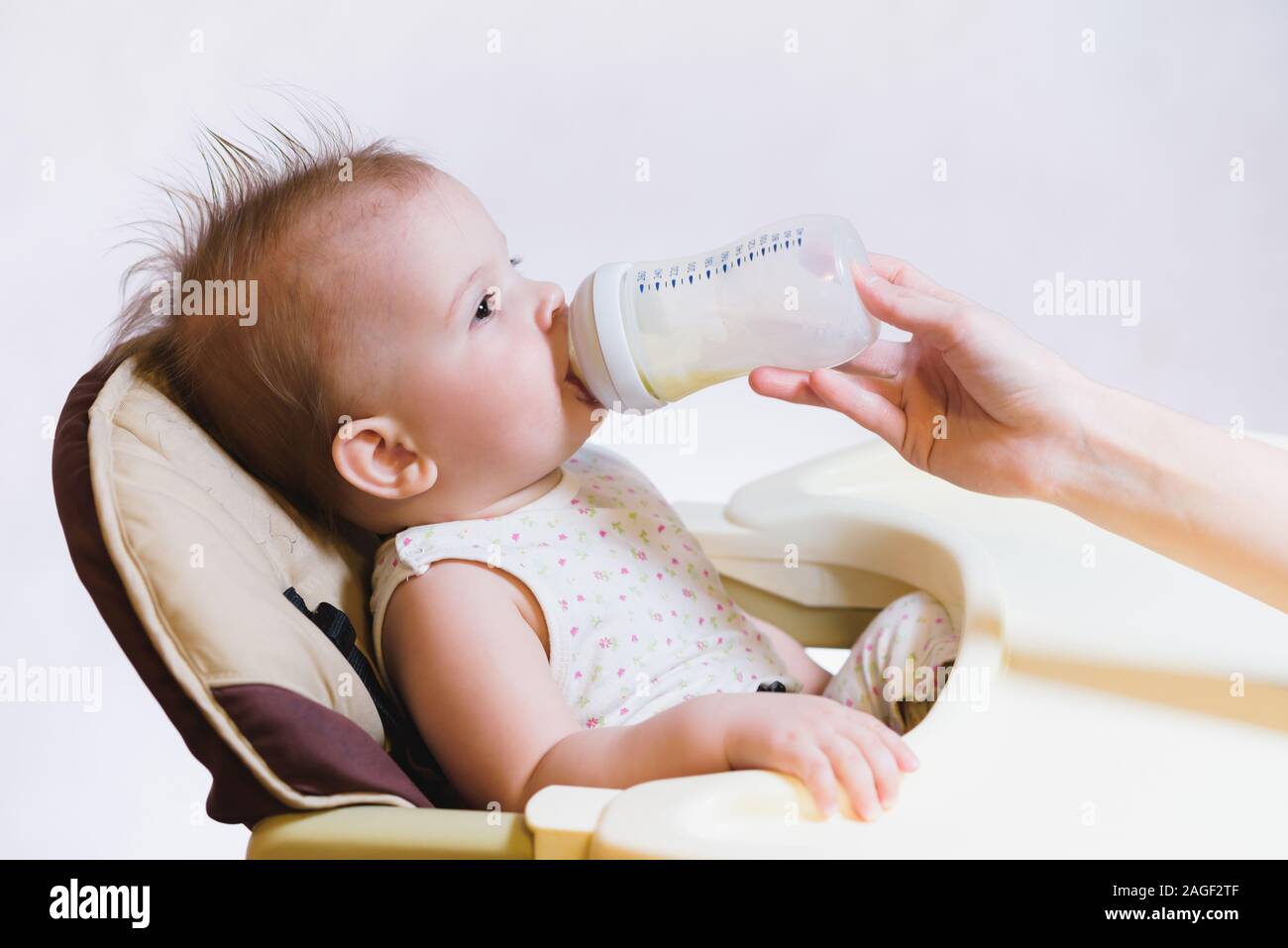 woman gives to drink baby milk in the house Stock Photo Alamy