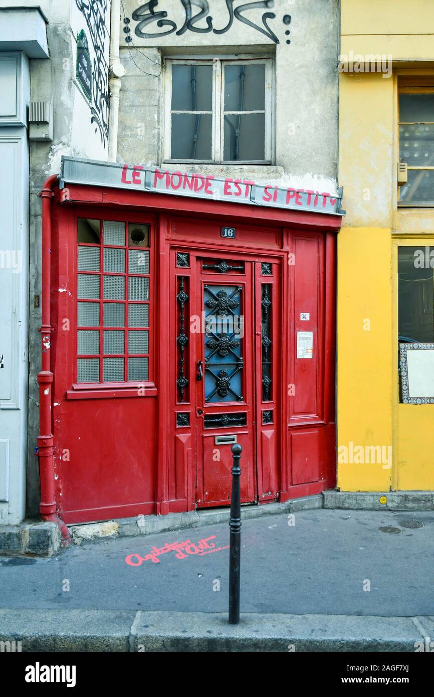 An old, red entrance door with graffiti in Rue Charlot, a street in Le Marais historic district in the 3rd arrondissement, Paris, France Stock Photo