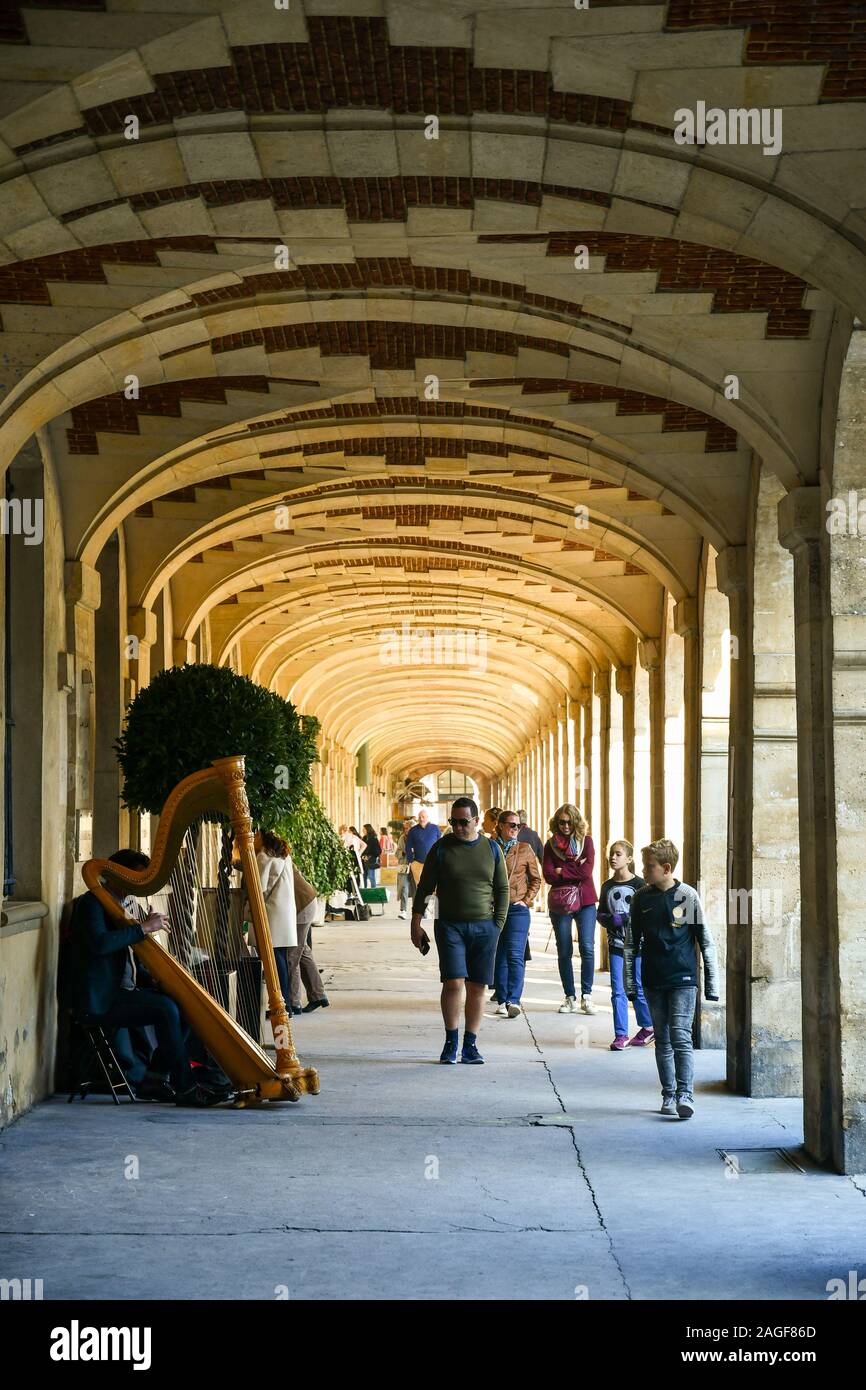 A street musician playing the harp under the porches of the famous Place des Vosges, a historic square in the Marais district, Paris, France Stock Photo