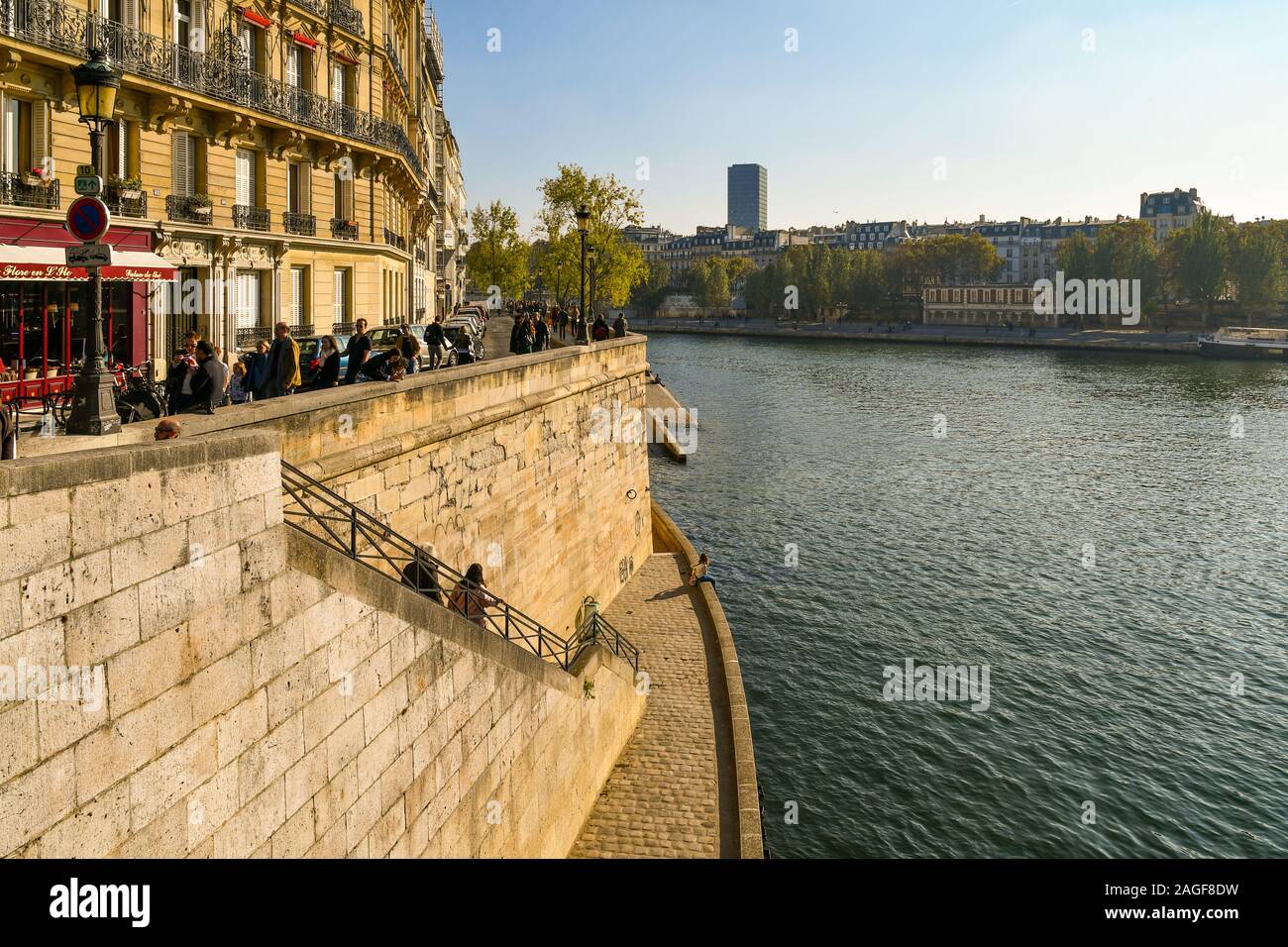 Scenic view of the Seine River from Pont Saint-Louis bridge with people and tourists in Quai d'Orléans river bank on Ile Saint-Louis, Paris, France Stock Photo