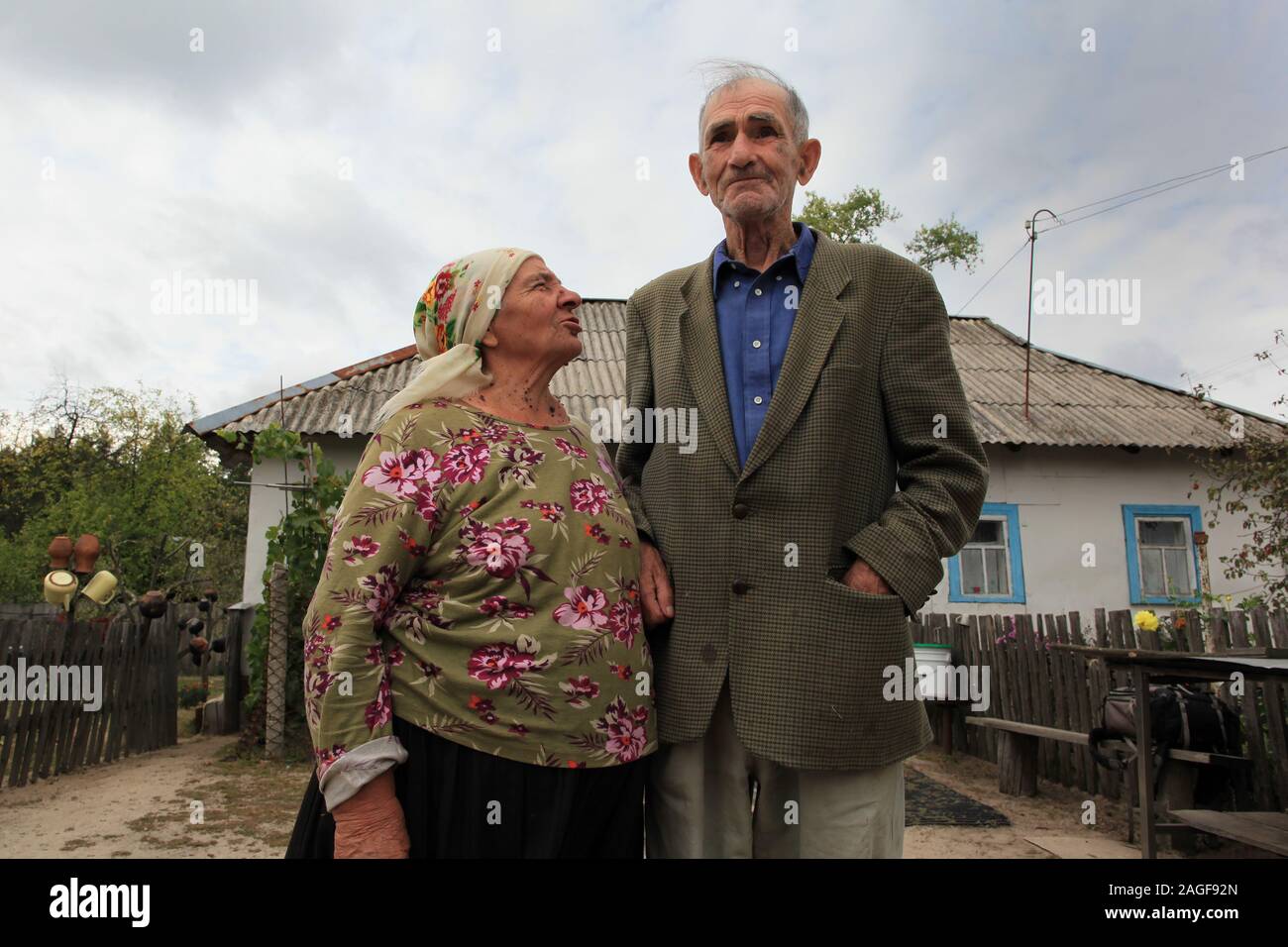 Ivan Ilchenko with his wife Maria in front of their house in the village Kupovate, located in the Chernobyl Exclusion Zone. Both are illegal residents (Samosely), who returned some months after the evacuation of the Chernobyl Exclusion Zone (following the Chernobyl disaster in April 1986) at their farm. Kupovate, Chernobyl Exclusion Zone, Ivankiv Raion, Kiev Oblast, Ukraine, Eastern Europe Stock Photo