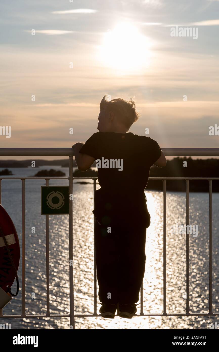 Young boy looking over the ship railing out to the ocean on a cruise ship Stock Photo