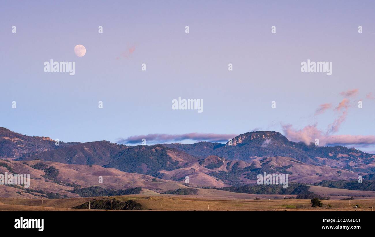 Almost full moon rising over hills and valleys, San Simeon, California Stock Photo