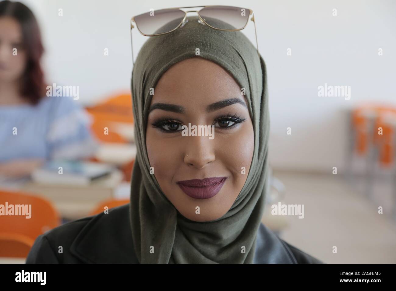 Portrait of muslim student girl mixed race wearing hijab at classroom desk. Stock Photo