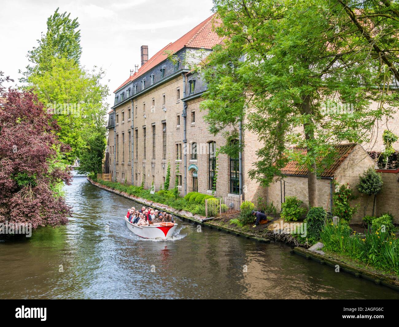 People on boat tour on Bakkersrei canal in old town of Bruges, Belgium Stock Photo