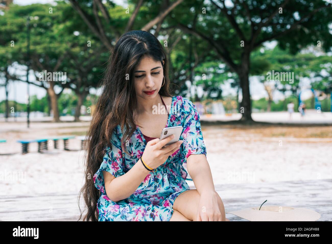 One long hair Asian Indian girl holding and looking at her mobile tablet  device at outdoor park Stock Photo  Alamy