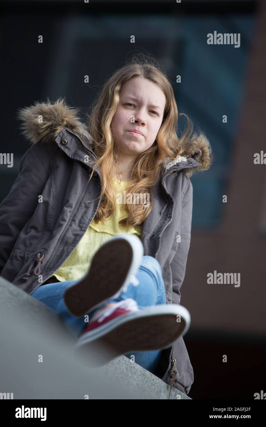Woman in casual clothing sitting dressed in converse trainers Stock Photo
