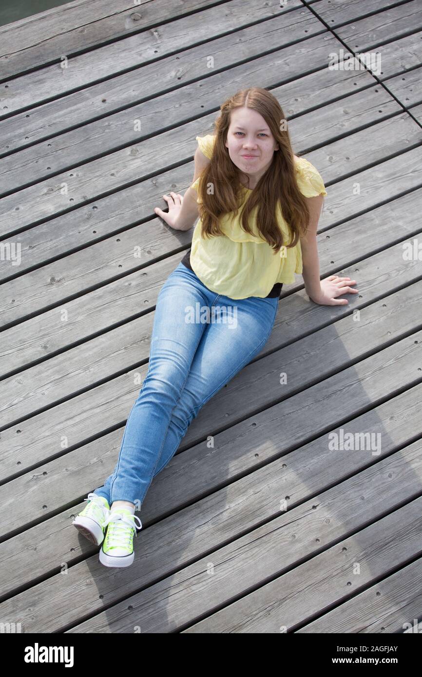 Woman in casual clothing sitting dressed in converse trainers Stock Photo