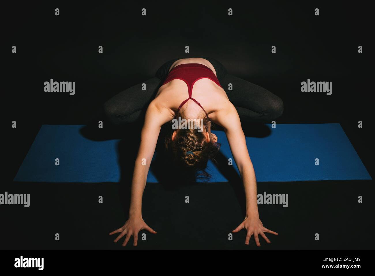 Woman practicing yoga in studio, yogi squat forward fold Stock Photo