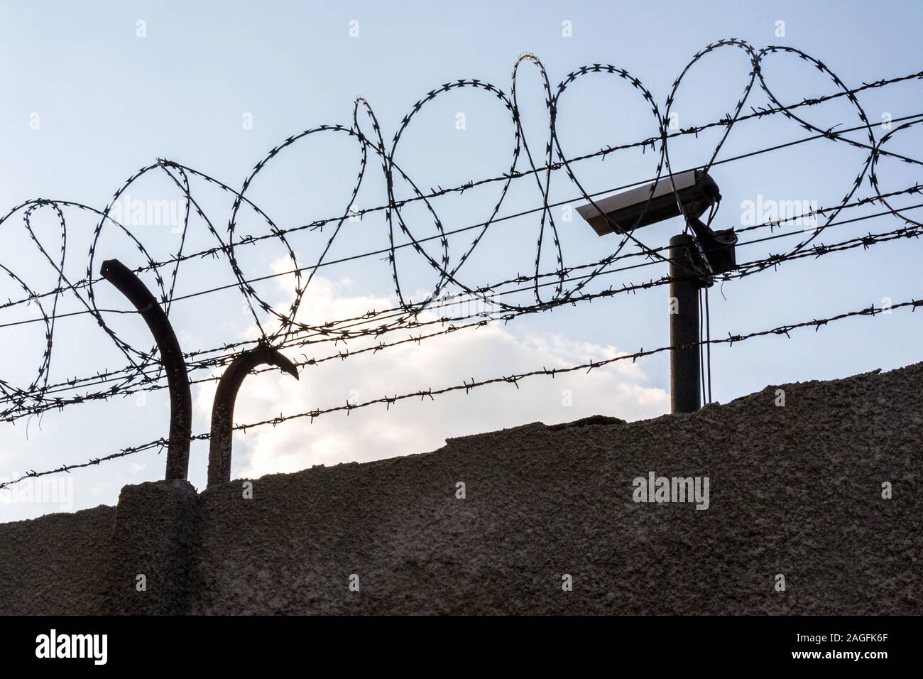 Security camera behind barbed wire fence on the wall, prison, security