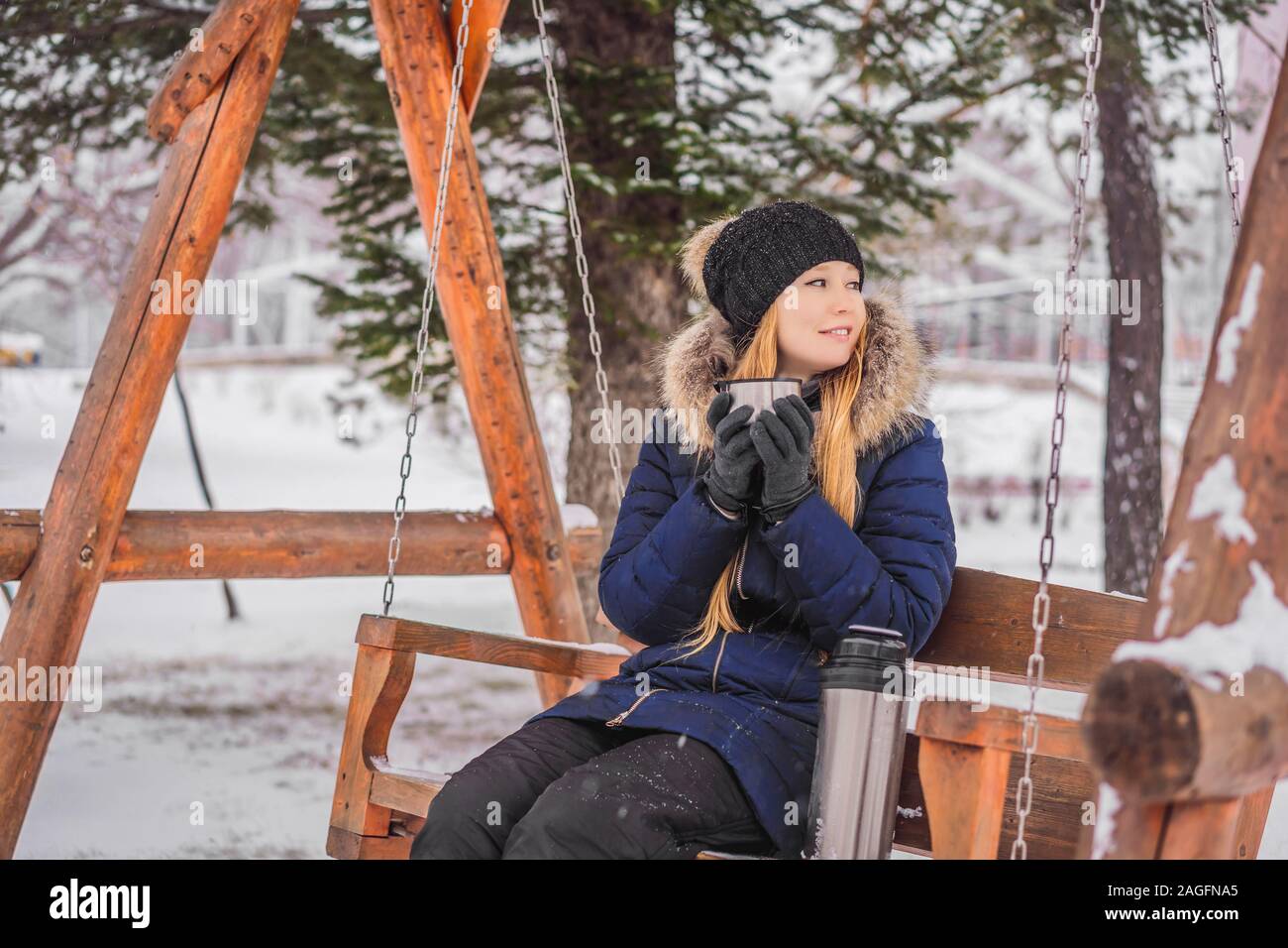 Woman drinks tea from a thermos on a winter day Stock Photo