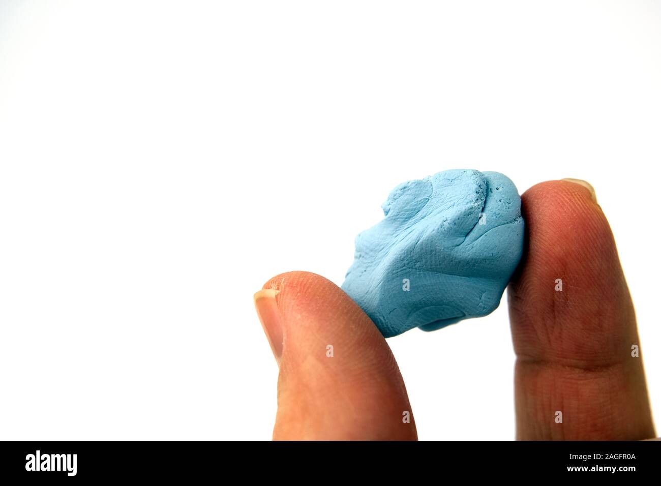 Blu Tack hold in hand. Close up photo of reusable and pressure sensitive adhesive paste commonly used to attach lightweight objects to walls. Stock Photo