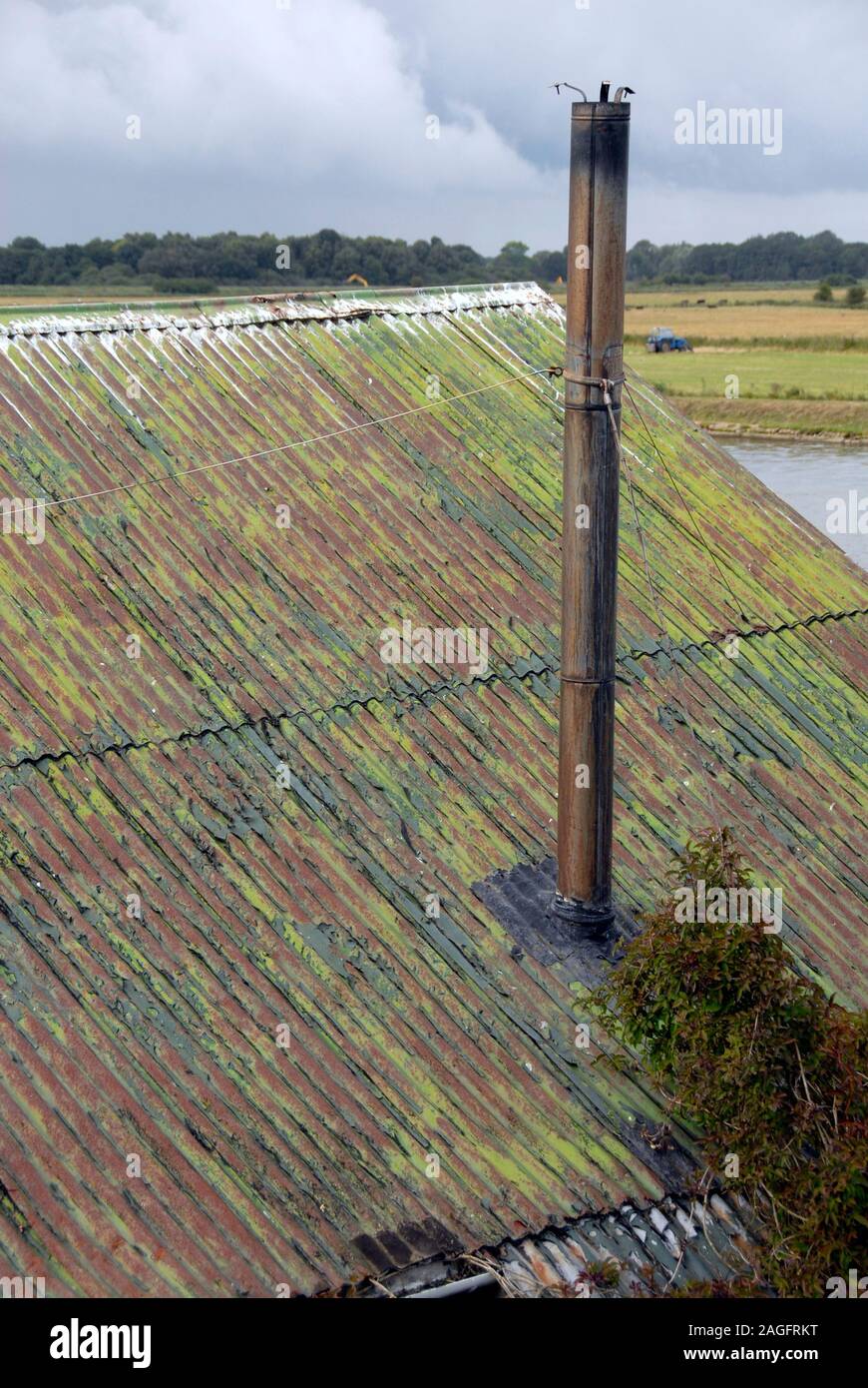 Chimney coming through corrugated iron roof, discoloured wth age, Norfolk, England Stock Photo