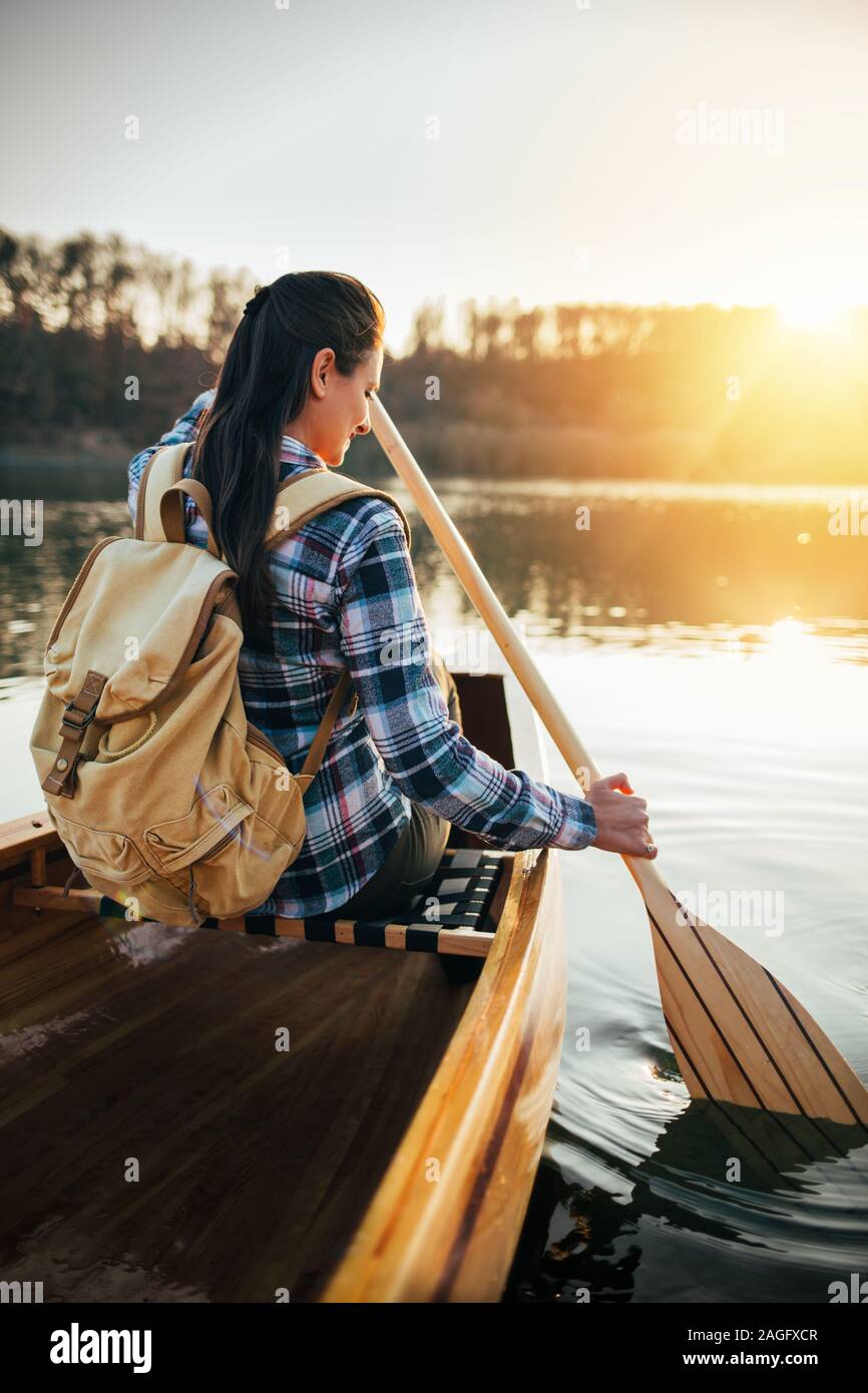 Rear view of woman canoeing on the sunset lake Stock Photo - Alamy