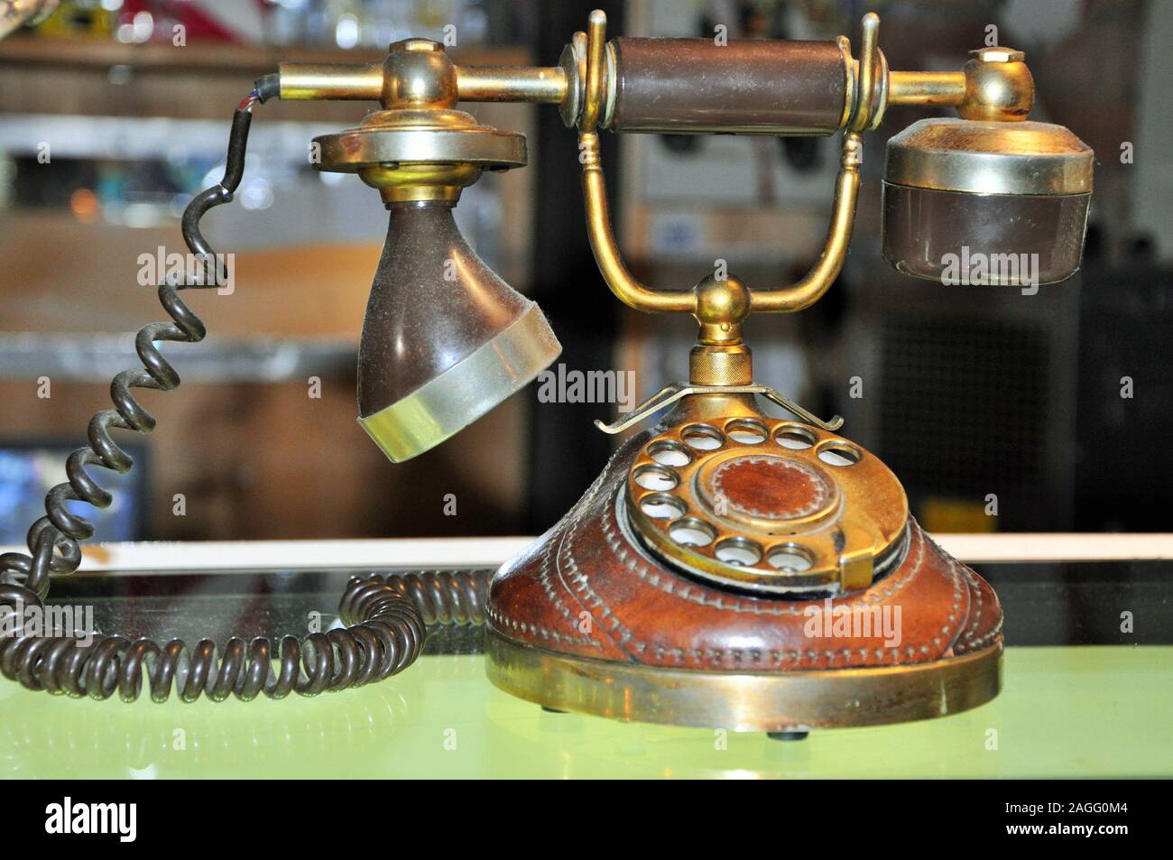 A corroded brown retro dial phone on a warm golden colored wooden deck. Stock Photo