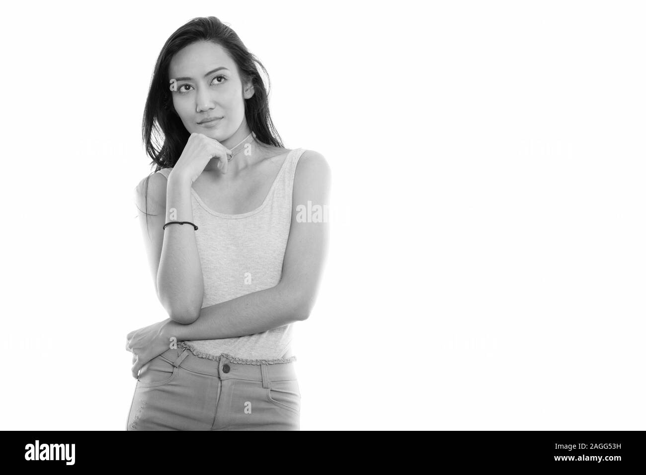 Studio shot of young beautiful Asian woman thinking while looking up ...