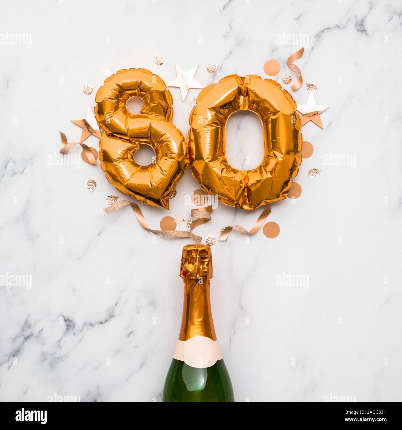Champagne bottle with gold number 80 balloon. Minimal party anniversary concept Stock Photo