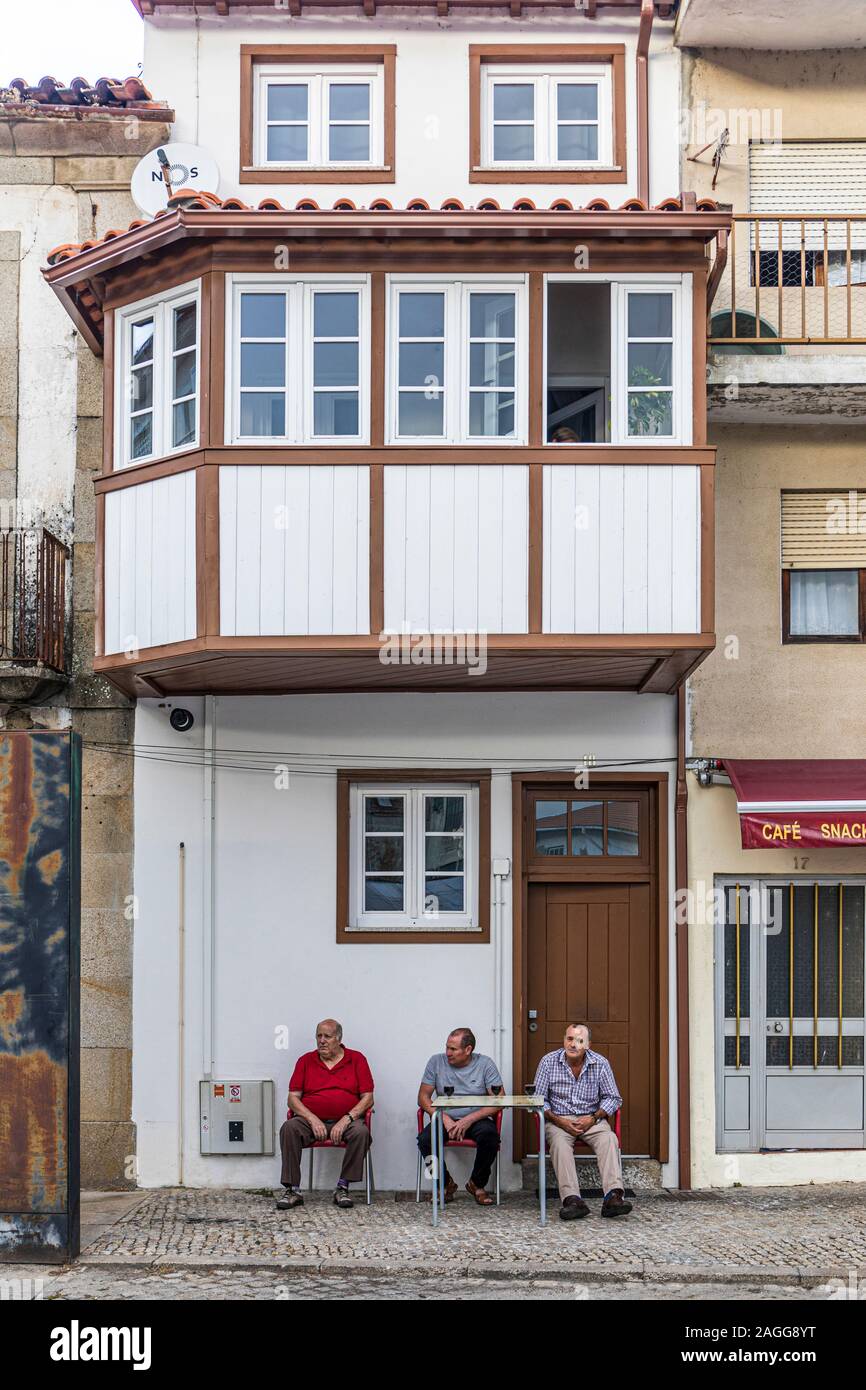 Three men seated in front of their home.  Chaves and Madalena, Portugal Stock Photo