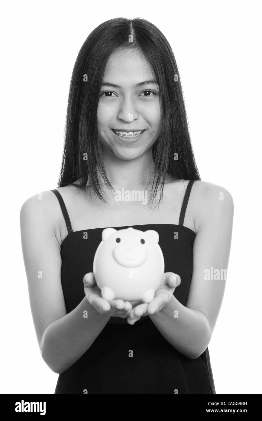 Close up of young happy Asian teenage girl smiling while holding piggy ...