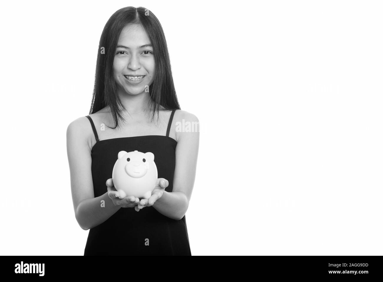 Studio shot of young happy Asian teenage girl smiling while holding ...