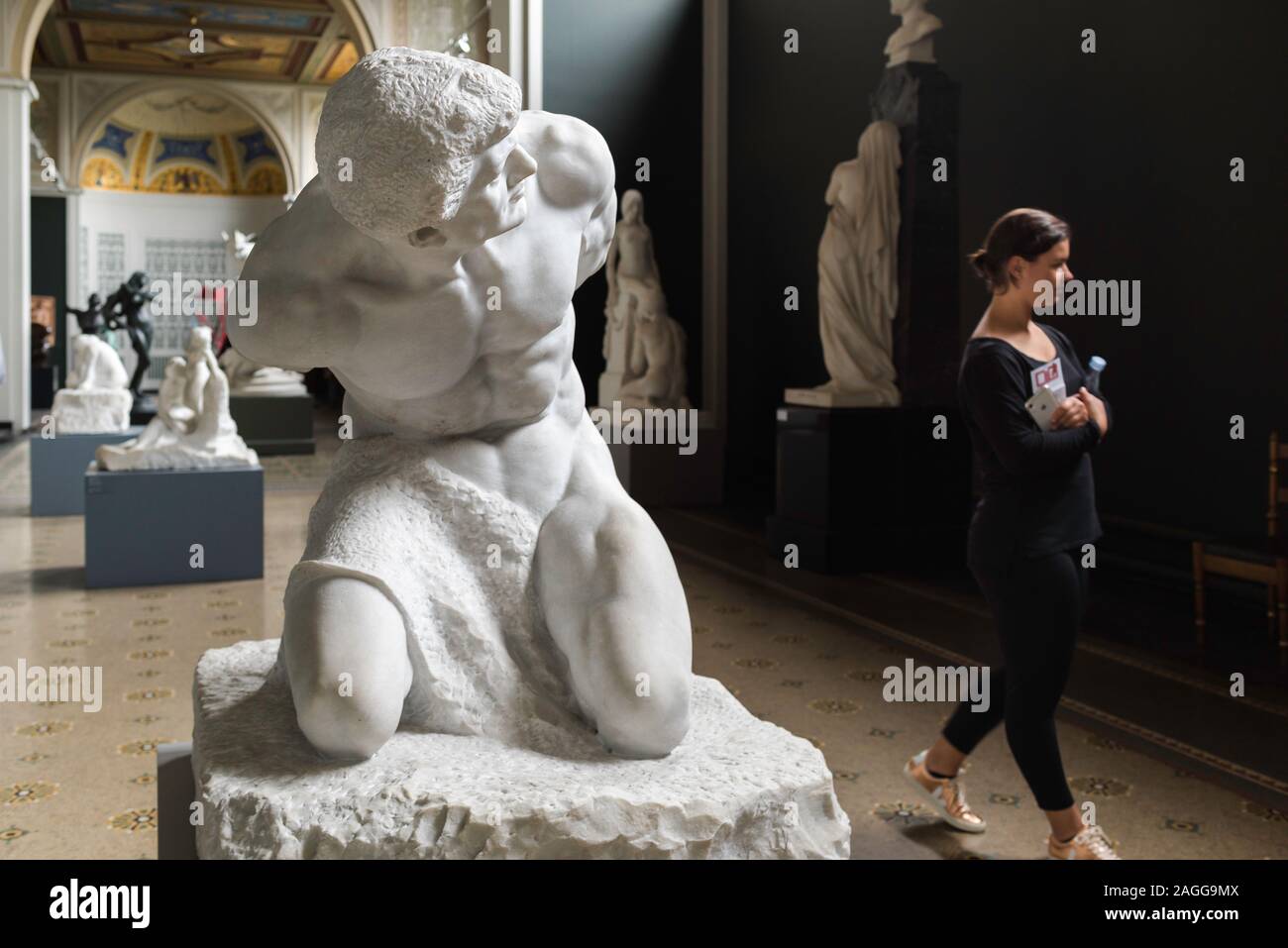 View of sculpture titled The Slave (Stephan Sinding 1913) and a young woman visiting the Ny Carlsberg Glyptotek museum in Copenhagen, Denmark. Stock Photo