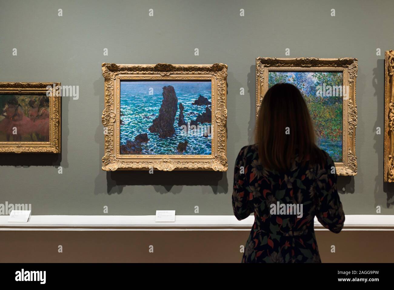 Woman gallery, rear view of a woman looking at  Les Pyramides At Port-Coton (1886) by Claude Monet, Ny Carlsberg Glyptotek museum, Copenhagen Denmark Stock Photo