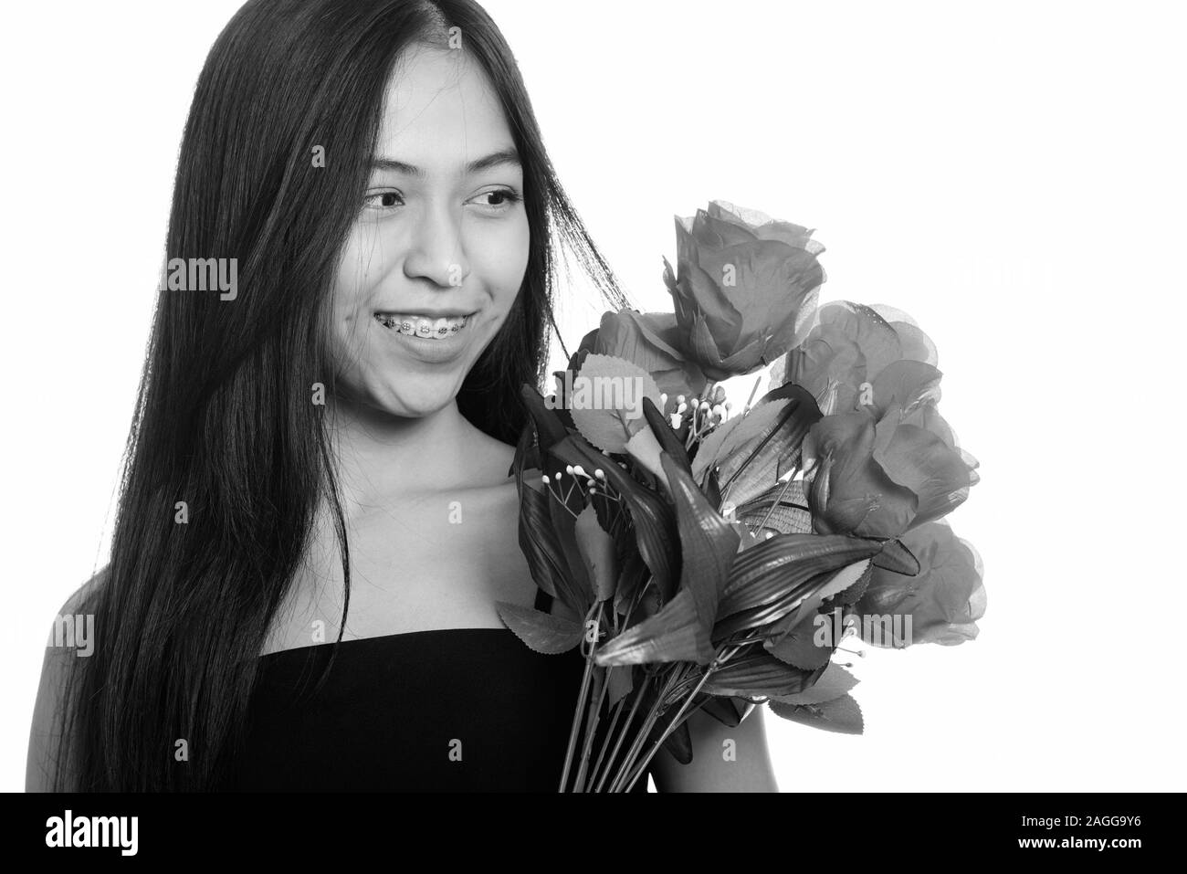 Young happy Asian teenage girl smiling while holding and looking at red ...