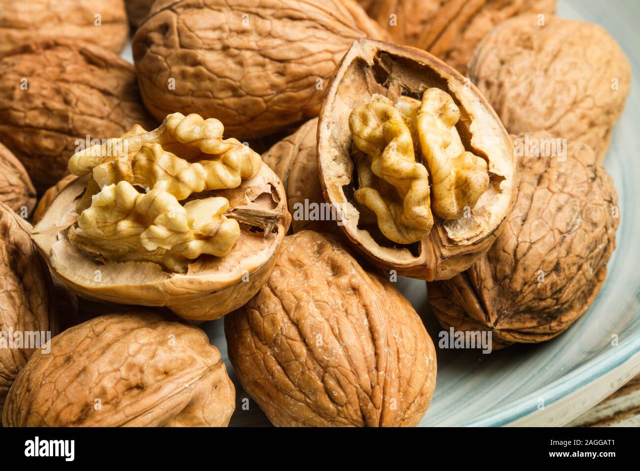 Walnuts in a light blue plate on a rustic wooden table Stock Photo