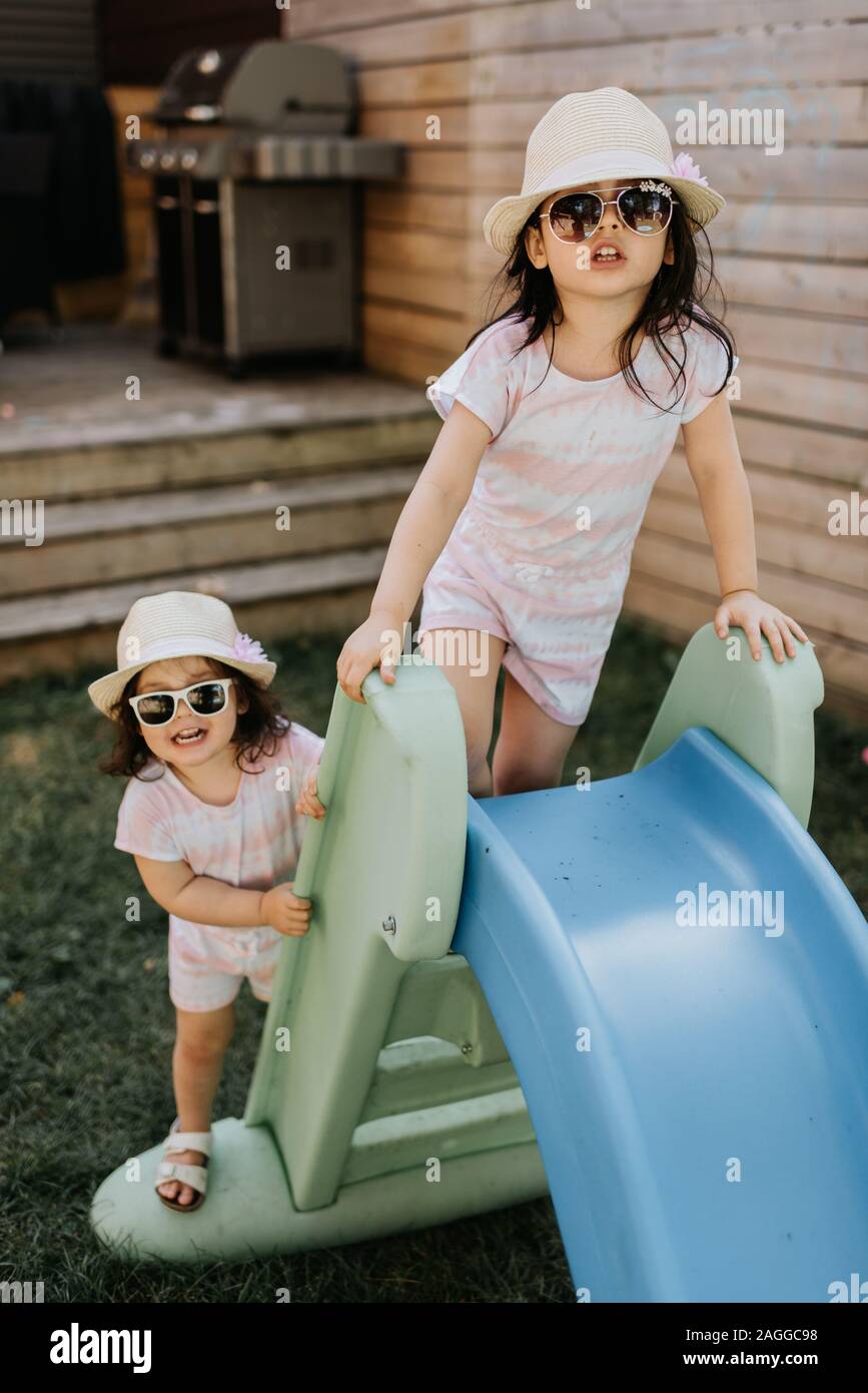 Sisters playing on slide in backyard Stock Photo