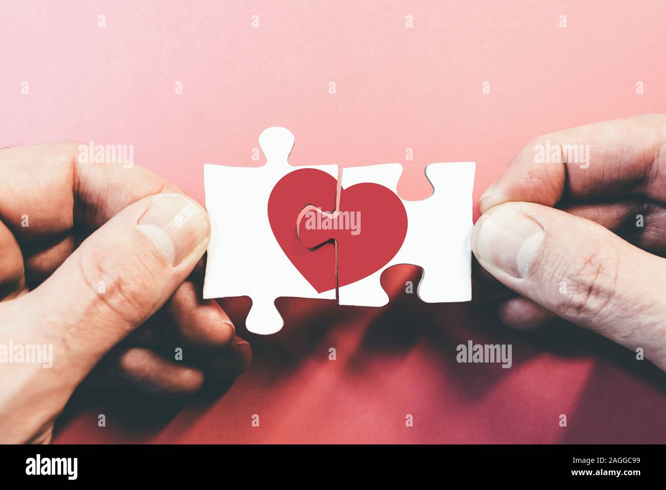 hands connecting or disconnecting jigsaw puzzle pieces with red heart, love or broken heart concept Stock Photo