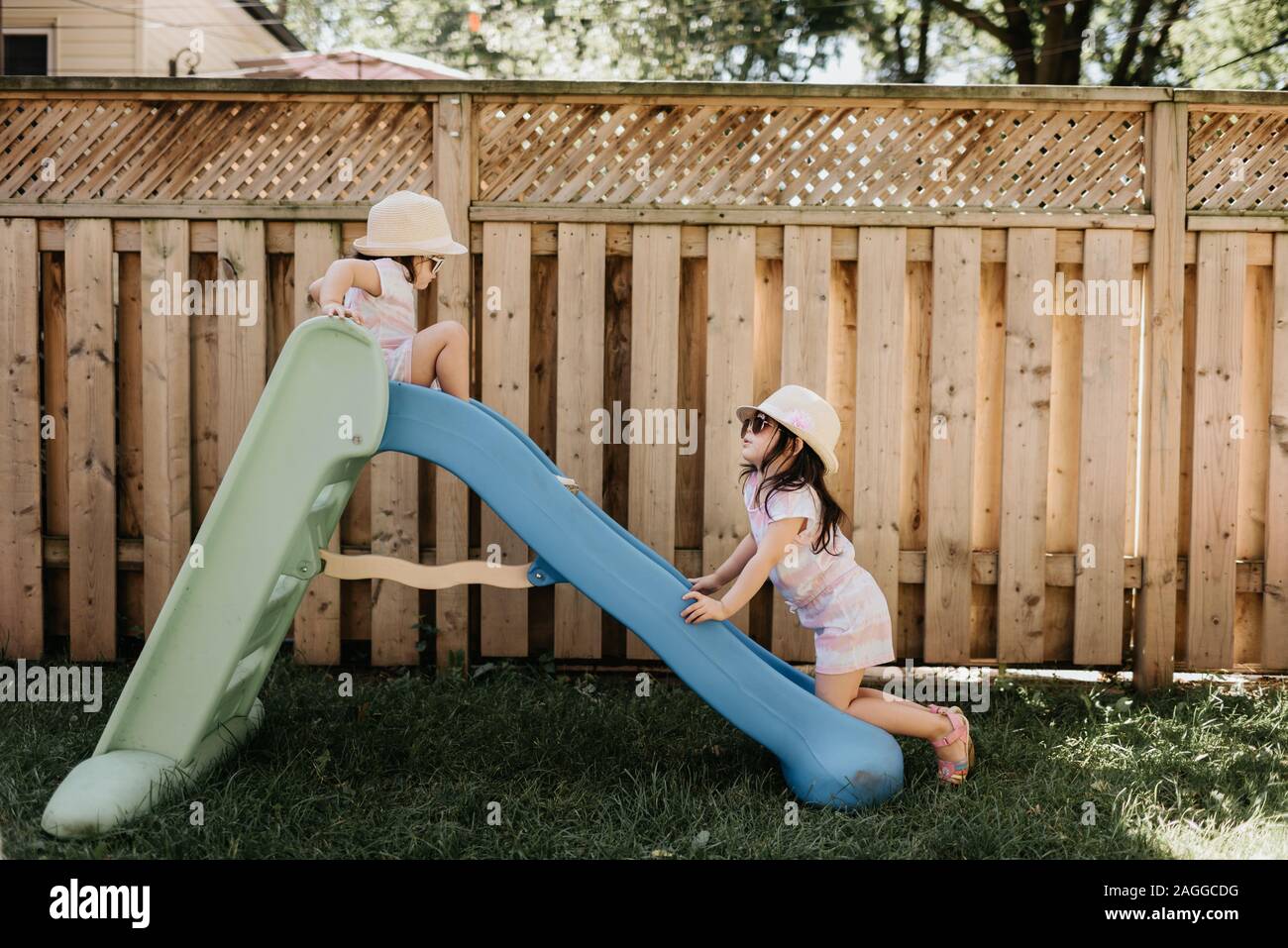 Sisters playing on slide in backyard Stock Photo