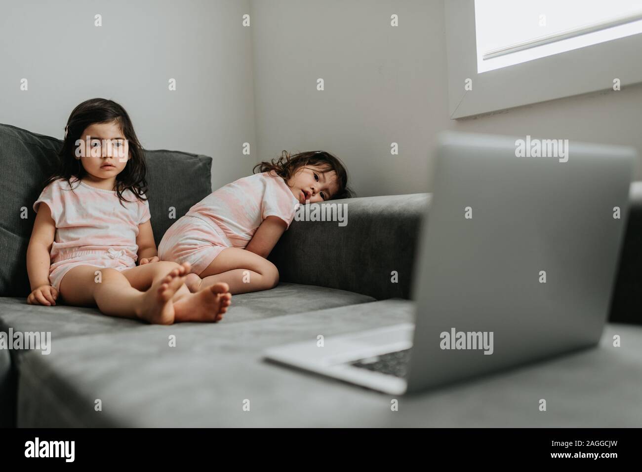 Sisters relaxing in front of laptop on couch Stock Photo - Alamy