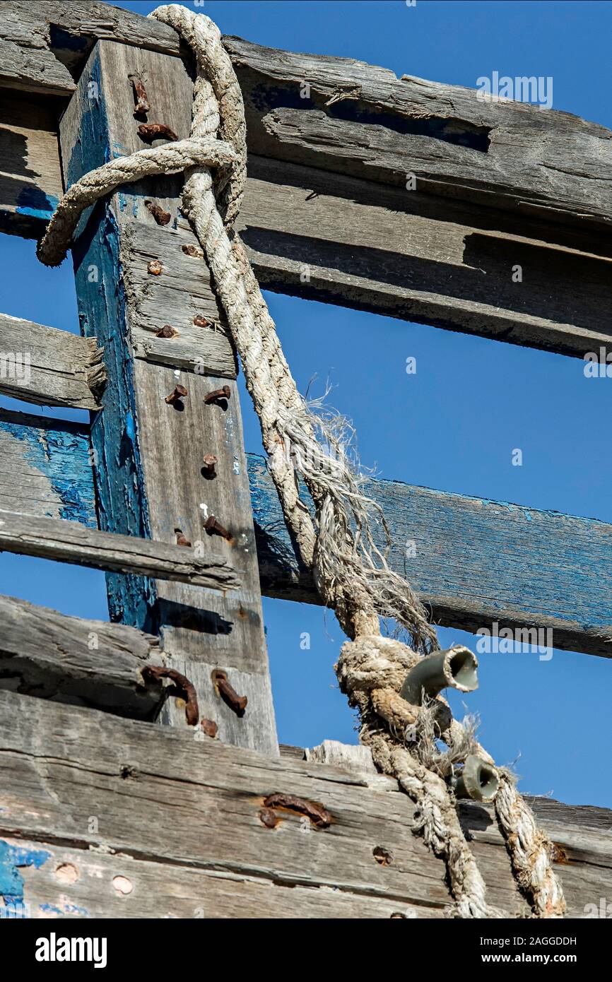 Old, frayed; mooring rope and peeling paint of old rotting hulk in the ...