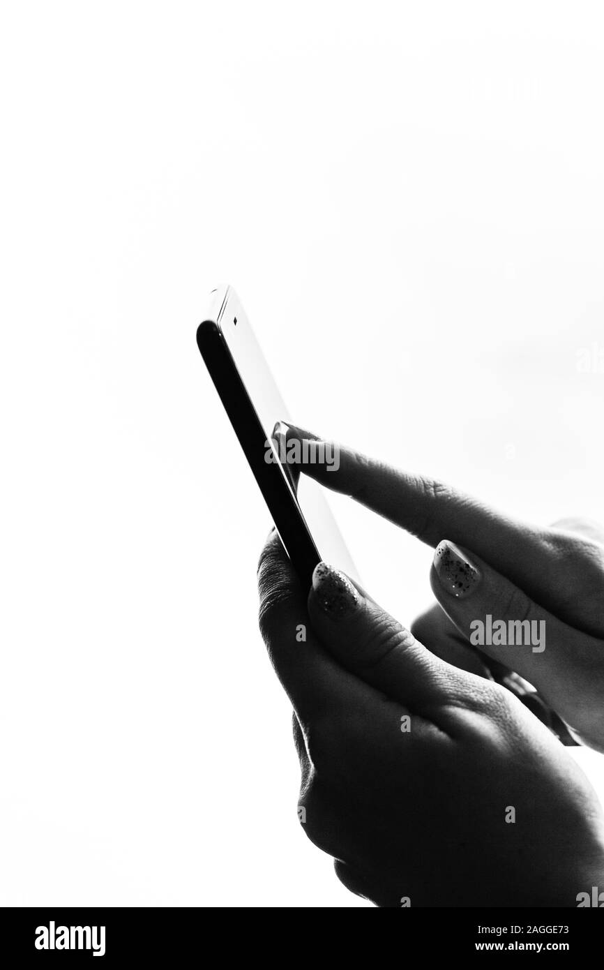 Woman hand holding a black smartphone in her hand. Teenage girl using a touchscreen smartphone, isolated on white Stock Photo