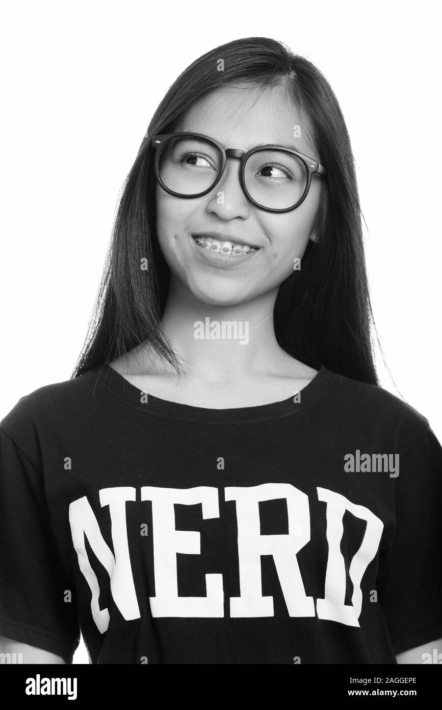 Close up of young happy Asian teenage nerd girl smiling while thinking