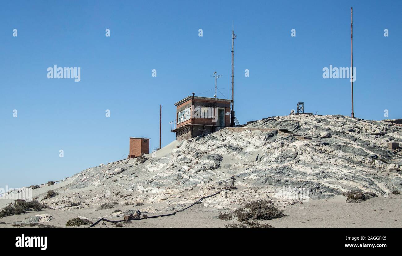 The old, derelict coastguard station shack perched on rocks on Diaz Point with radio masts still in place. Stock Photo