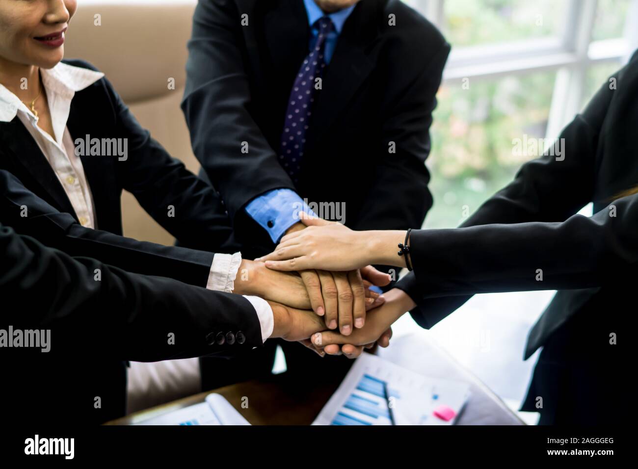 business team working at trendy loft office. Young mixed race group of people puts palm together on the centre. Teamwork of happy guys, colleagues. Stock Photo