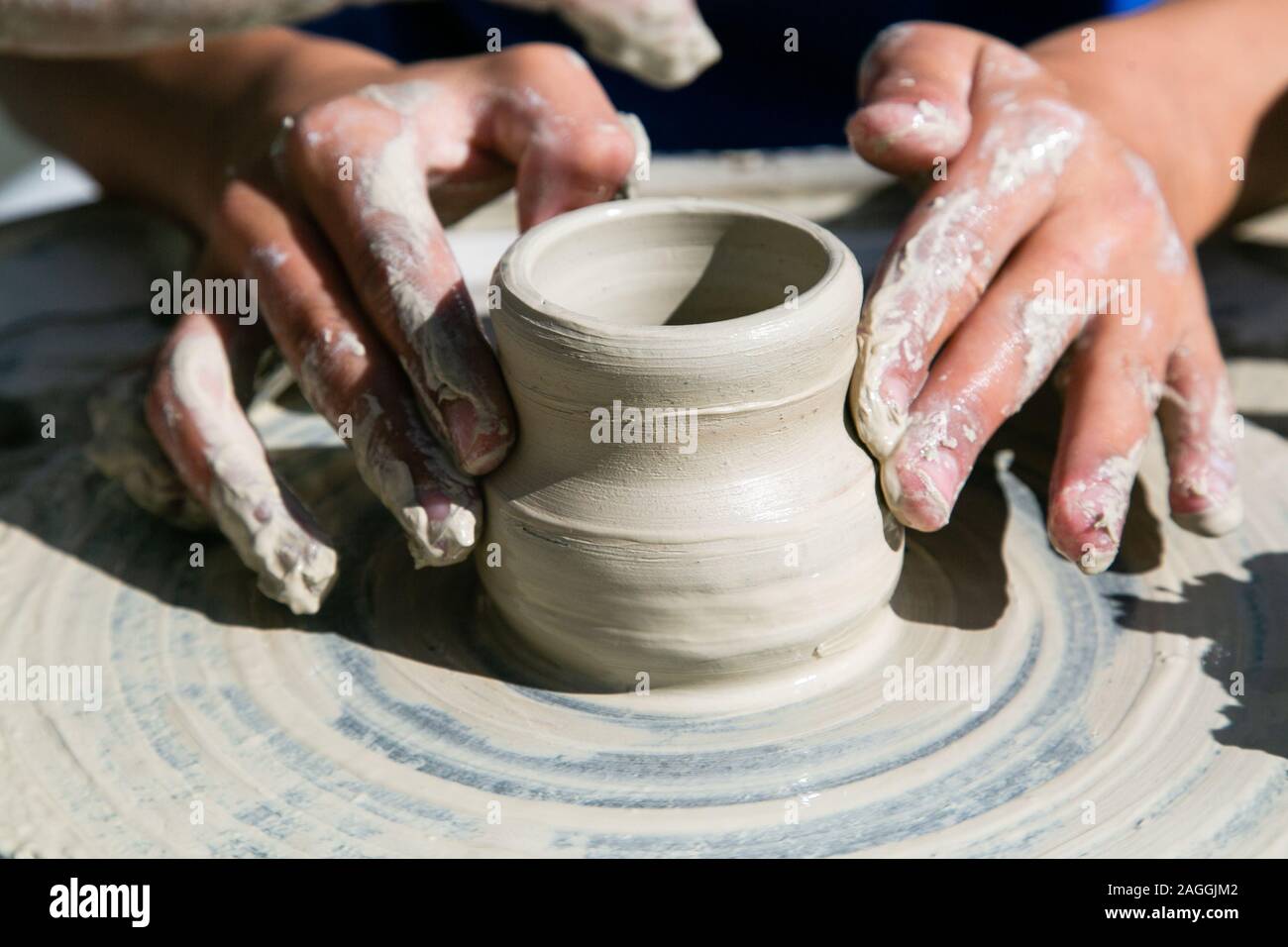 Womans hands working of ceramics with clay on a potter wheel Stock Photo