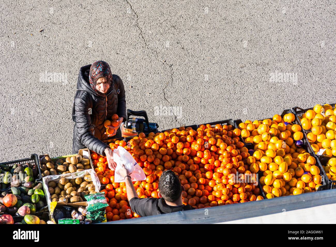 Capileira, La Alpujarra, Alpujarras, Granada region, Andalusia, Spain. Woman buys oranges and plastic bag at the marketplace in the village. Stock Photo