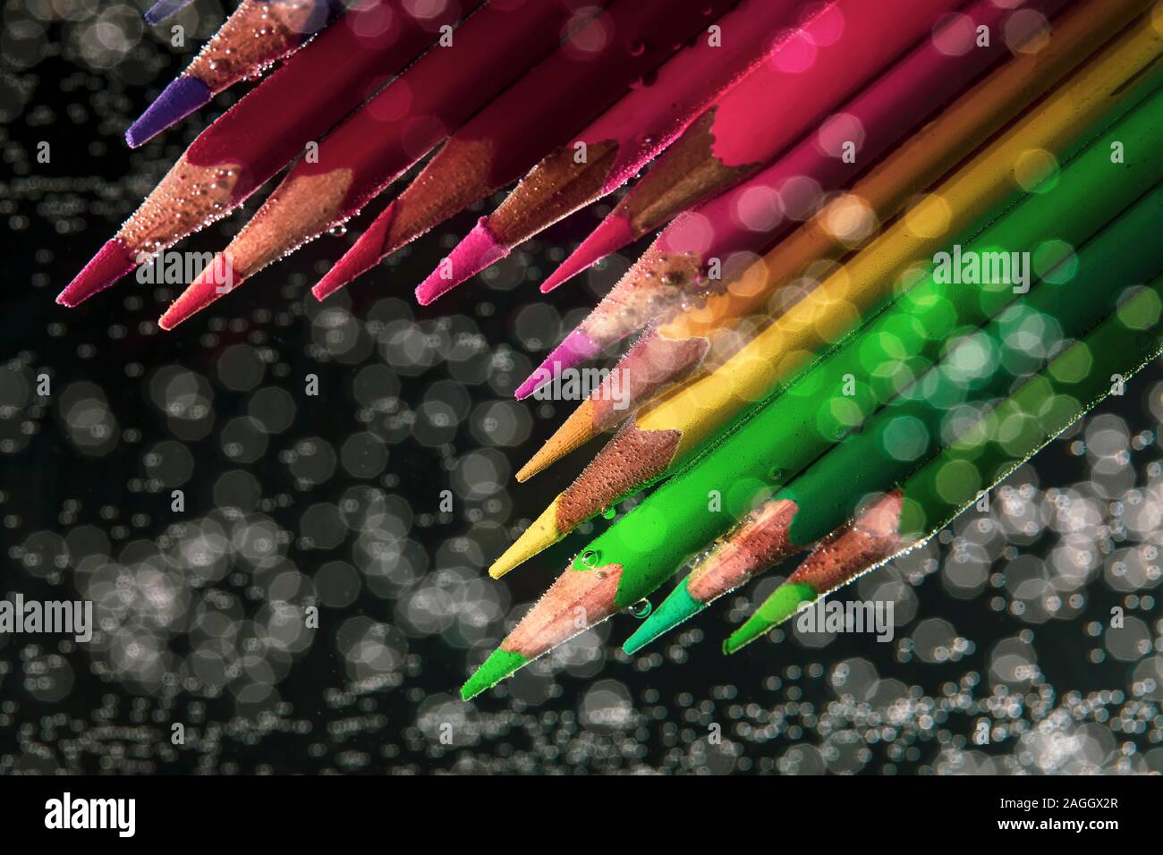 Colored pencils in water with drops on a bokeh background. Background blurred multicolored pencils Stock Photo
