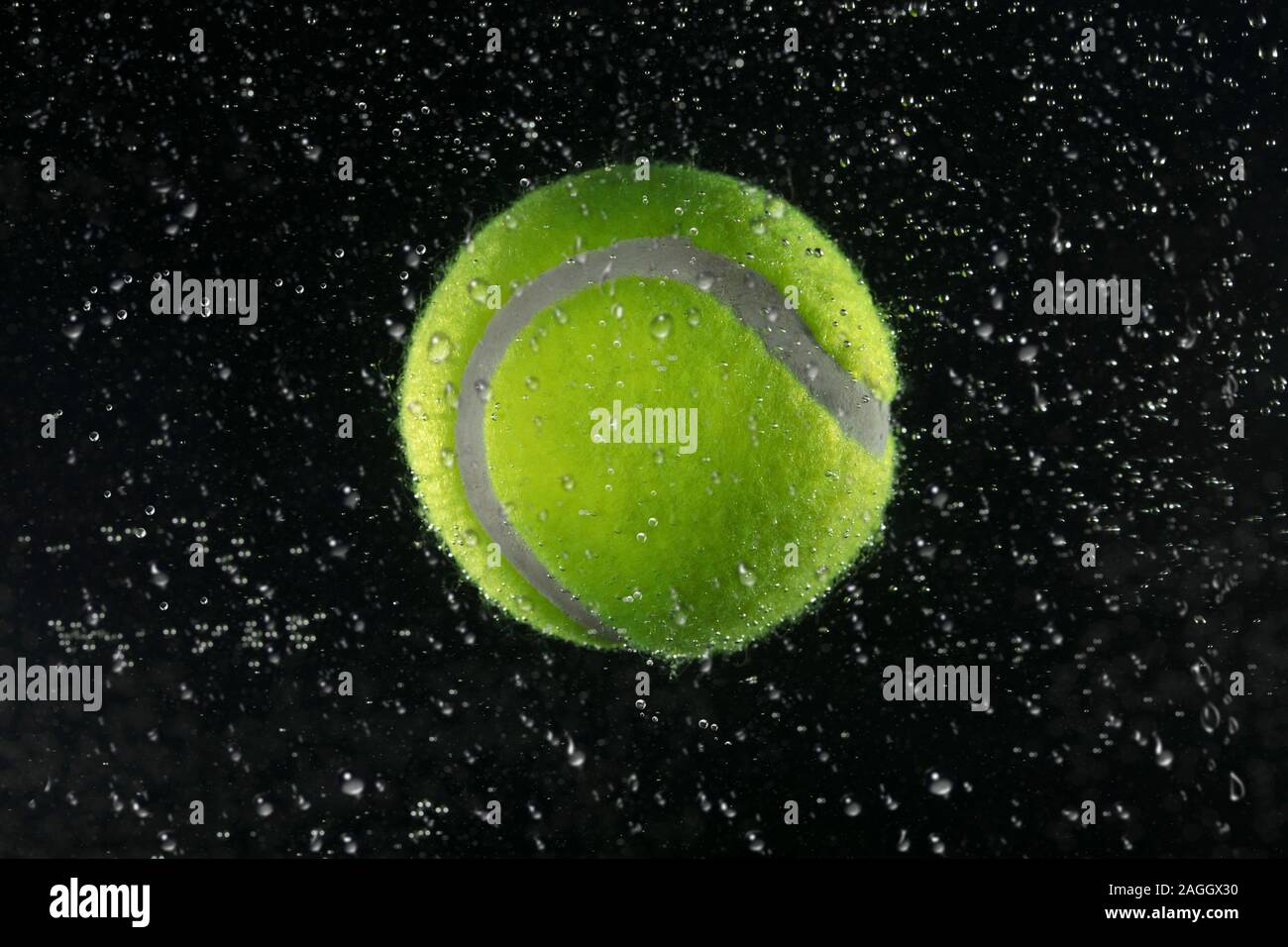 Tennis ball in the water on a dark background Stock Photo