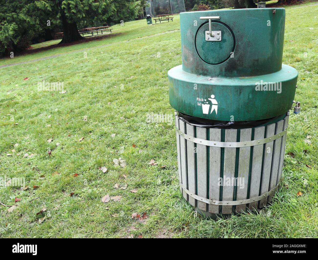 https://c8.alamy.com/comp/2AGGXME/green-garbage-can-with-animal-proof-lid-and-the-words-pitch-in-beside-a-pictogram-of-a-person-dropping-garbage-in-a-bin-on-a-grassy-slope-2AGGXME.jpg